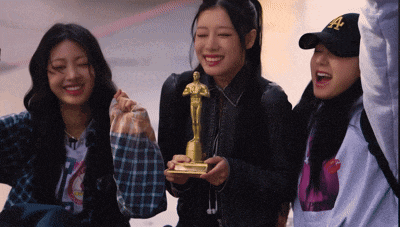 a girl in a la hat holds a statue of a man