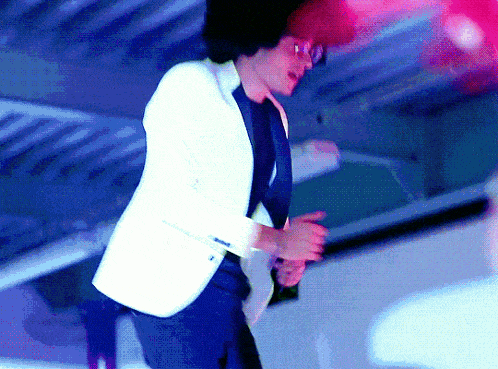 a man in a white jacket and black tie dancing