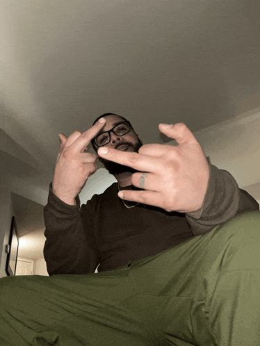 a man with glasses and a tattoo on his finger is giving a middle finger