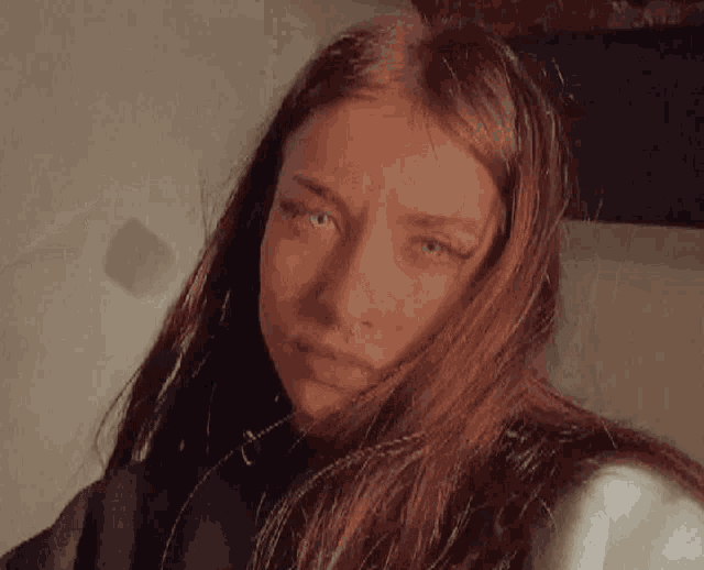 a woman with long brown hair and a nose ring looks at the camera .