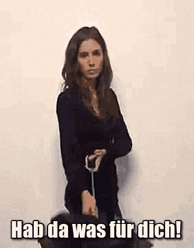 a woman is standing in front of a white wall with the words hab da was fur dich written on the bottom of the image .