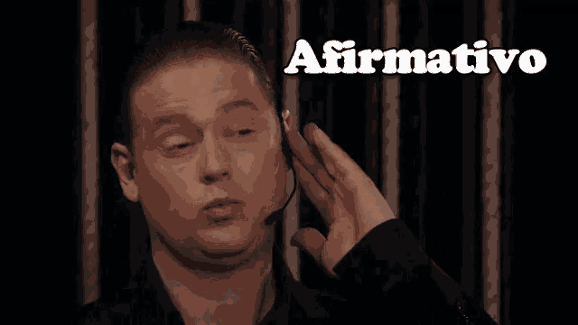 a man wearing a headset covering his ear with his hand and the word afirmativo above him