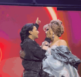 two women are dancing on a stage and one of them is pointing at the other .