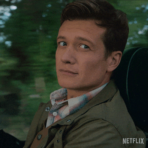 a man is sitting in a car with a netflix logo on the back of his jacket