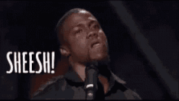 a man in a black shirt and tie is standing in front of a microphone and says sheesh .