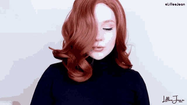a woman with red hair is wearing a black turtleneck sweater and covering her face with her hair .