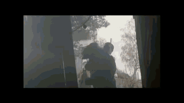 a man is holding a woman in his arms in a dark room in a video .