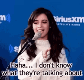 a woman is singing into a microphone and says `` haha ... i don 't know what they 're talking about ''