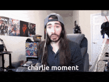 a man with long hair and a hat is sitting in a chair with the words charlie moment below him