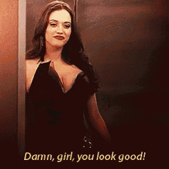 a woman in a black dress is standing next to a wall and says " damn girl you look good "