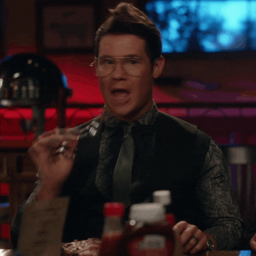 a man with glasses is eating a steak with a fork