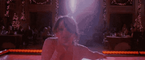 a woman is dancing on a dance floor in a room with christmas trees in the background .