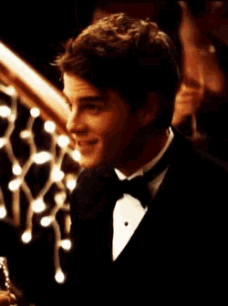 a man in a tuxedo is holding a glass in his hand