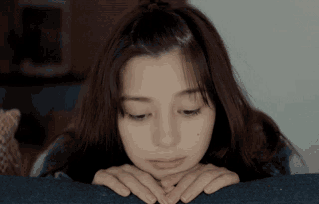 a woman laying on a couch with her hands on her chin