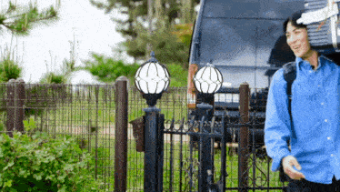 a man in a blue shirt stands in front of a gate