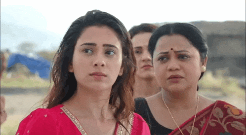 a group of women are standing next to each other and one of them is wearing a red dress .