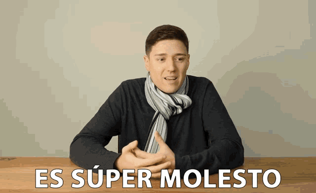 a man with a scarf around his neck is sitting at a table with the words es super molesto below him