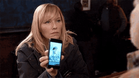 a woman is holding a cell phone with a picture of a man on the screen