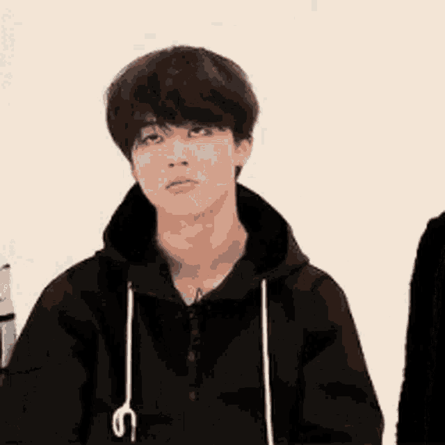 a young man in a black hoodie is making a face .
