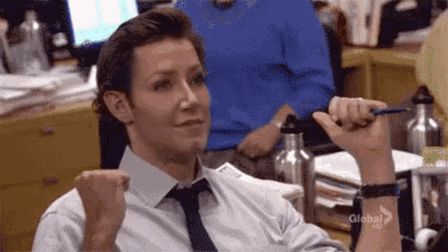 a man in a tie is sitting at a desk holding a pen .
