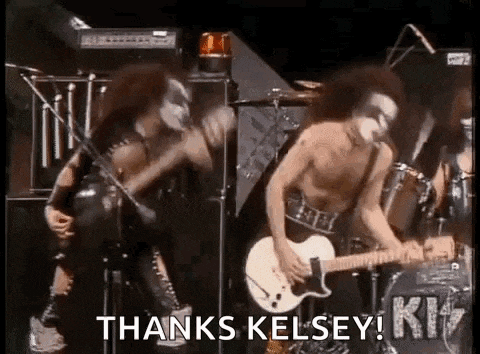 a man is playing a guitar on a stage in front of a microphone while another man kisses him .
