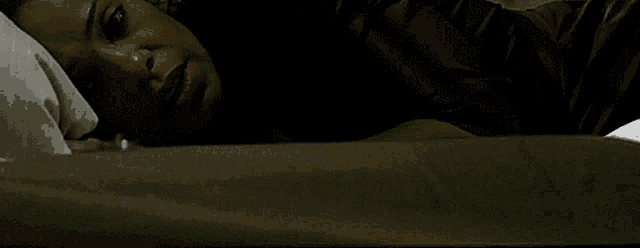 a woman is laying on a bed with her head on a pillow and her eyes closed
