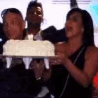 a woman is holding a cake with candles on it