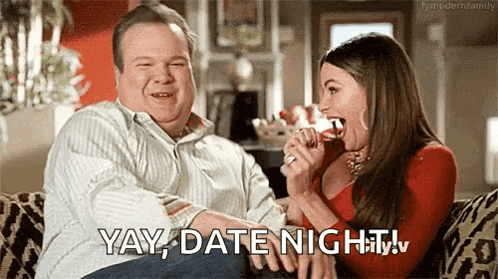 a man and a woman are sitting on a couch and the woman is holding a glass of wine in her mouth .