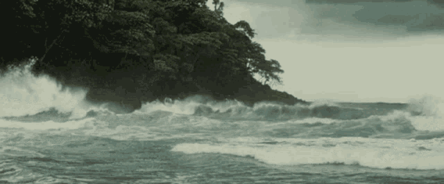 a stormy ocean with waves crashing against a rocky shoreline