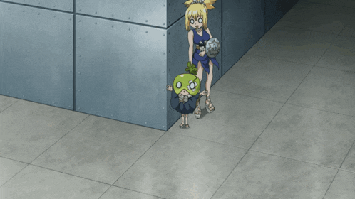 a girl in a blue dress is standing in a corner next to a green object