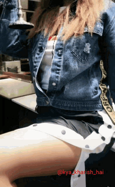 a woman wearing a denim jacket and white shorts is sitting on a chair with the hashtag @kya_khansh_hai