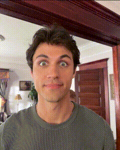 a man in a green shirt is making a funny face in a living room