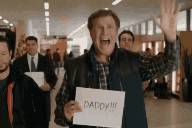a man holding up a sign that says daddy