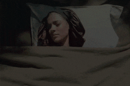 a woman laying in bed with a pillow that has her head on it