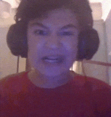 a person wearing headphones and a red shirt making a funny face