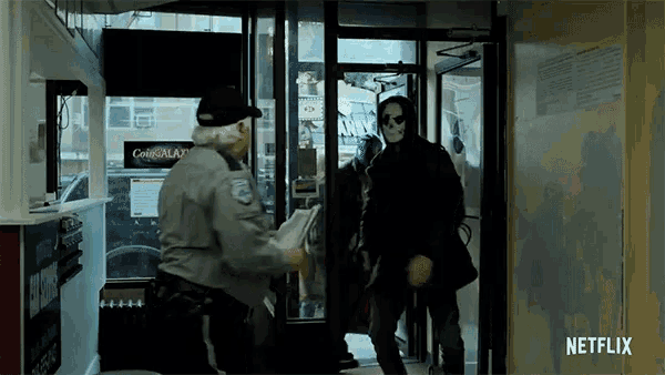 a man in a mask is being escorted by a security guard