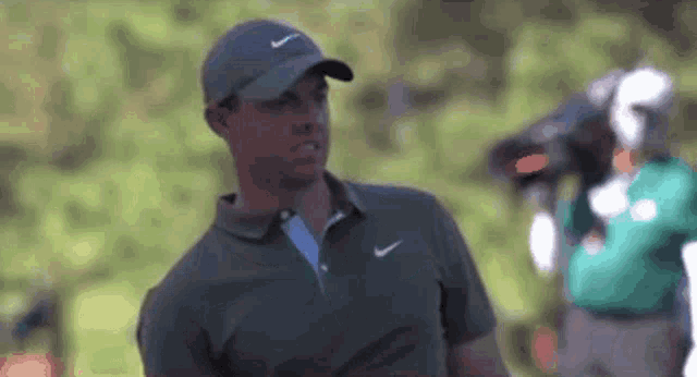a man wearing a hat and a nike shirt is playing golf .