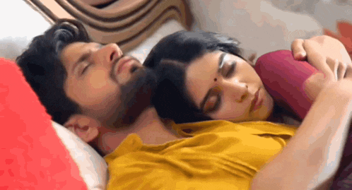a man and a woman are sleeping on a bed . the man is wearing a yellow shirt .