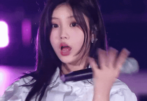 a close up of a girl holding a microphone in her hand .