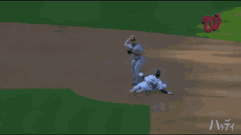 a baseball player is laying on the ground while a washington nationals logo can be seen in the background