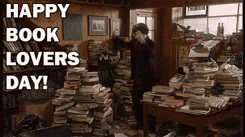 a man is standing in a room filled with lots of books and a sign that says happy book lovers day .