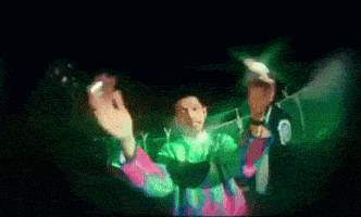 a man in a green and pink sweater is dancing