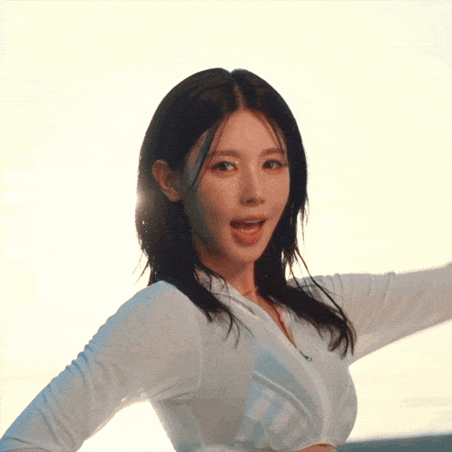 a woman in a white shirt with her arms outstretched looks at the camera