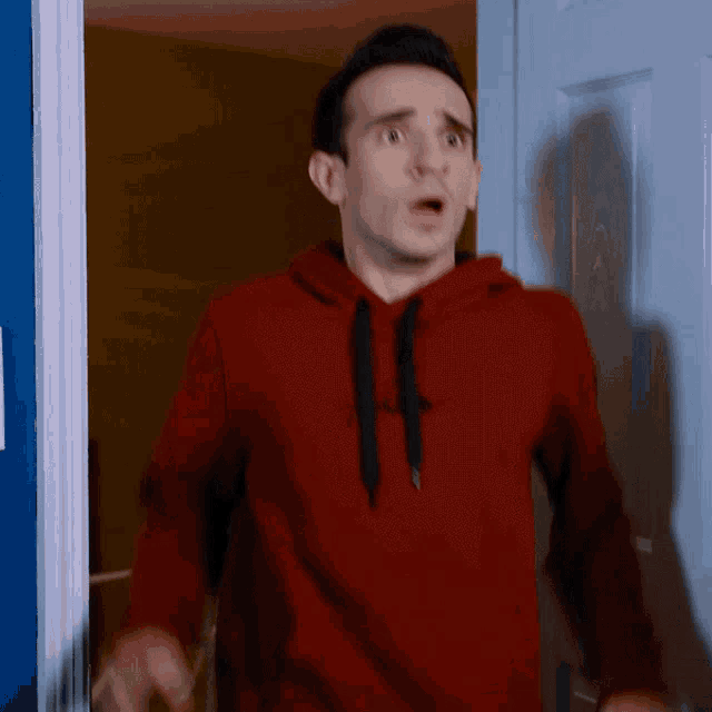 a man in a red gap hoodie stands in front of a door