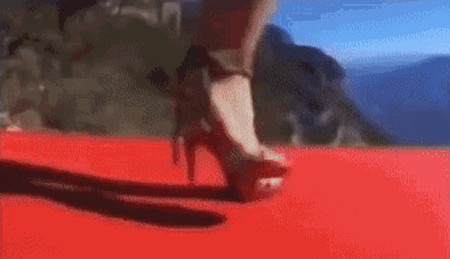 a woman is walking on a red carpet wearing high heels .