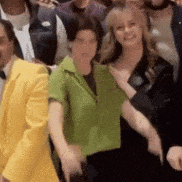 a woman in a green shirt is standing in front of a group of people .