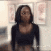 a woman in a black shirt is standing in front of a wall with paintings on it .
