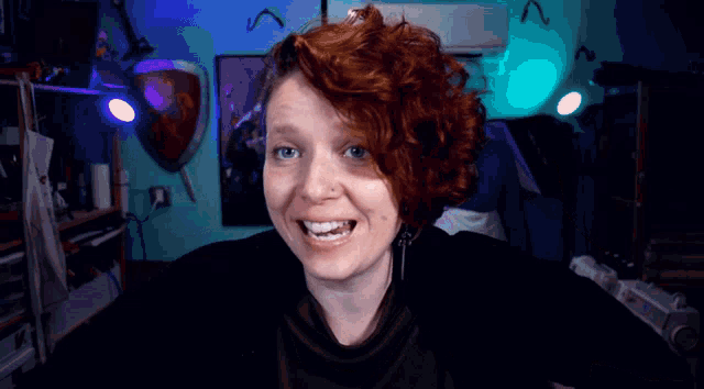a woman with red hair looks at the camera with a shield in the background