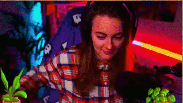 a woman wearing headphones and a plaid shirt is sitting in front of a microphone