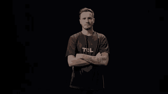 a man with his arms crossed is wearing a tcl t-shirt